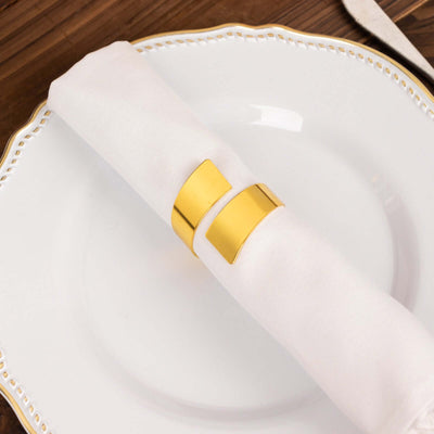 Gold napkin ring on a white napkin placed on an elegant plate.