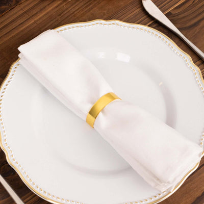 White napkin with gold ring on an elegant plate setting.