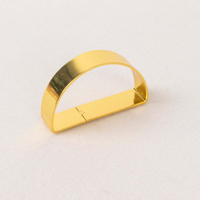 Gold metal half-moon shaped clip for organizing papers or materials.