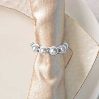 Elegant pearl napkin ring with sparkling accents on a silk napkin.