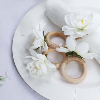 Decorative napkin rings with artificial flowers on a white plate.