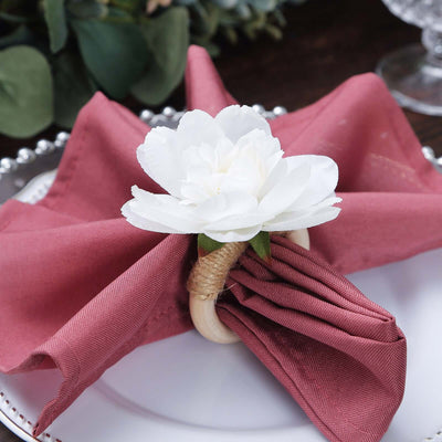 Elegant table setting with a pink napkin and white flower decoration.