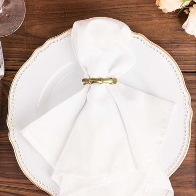 Elegant white napkin styled on a decorative plate with a gold napkin ring.