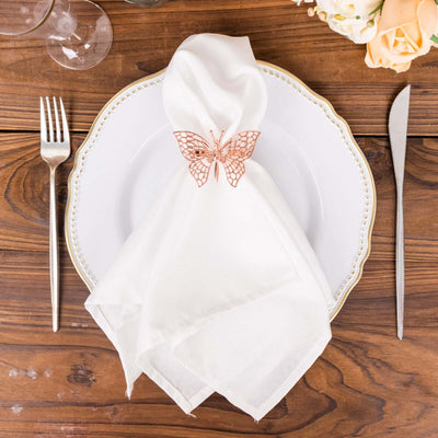 Elegant white napkin with rose gold butterfly napkin holder on a decorative plate.