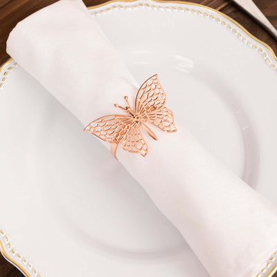 Rose gold butterfly napkin ring on a white napkin.
