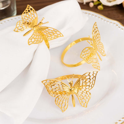 Gold butterfly napkin rings set on a plate with a napkin.