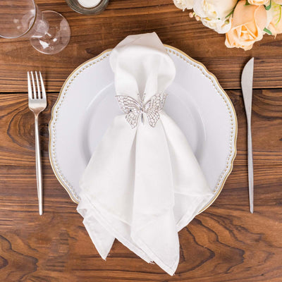 Elegant white napkin with butterfly napkin ring on a styled dinner plate.