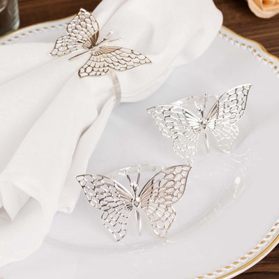 Silver butterfly napkin holders on a decorative plate.