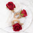 Red rose napkin rings on a white plate with a napkin.