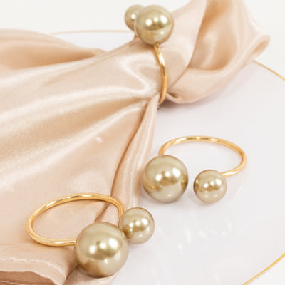 Gold ring set with pearl accents on a satin napkin.