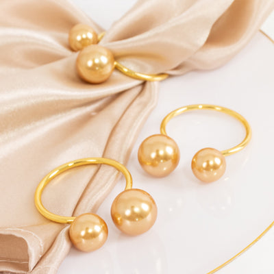 Gold pearl ring set on elegant fabric backdrop.