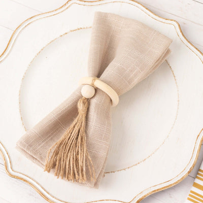 Natural linen napkin with wooden ring and tassel on decorative plate.