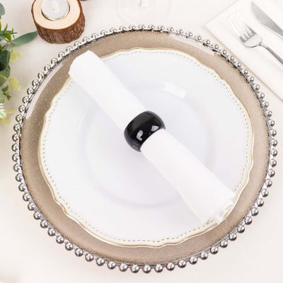 Elegant dinner plate with a black napkin ring on a decorative charger.