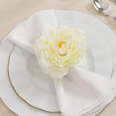 Elegant white peony flower on a napkin atop a decorative plate.