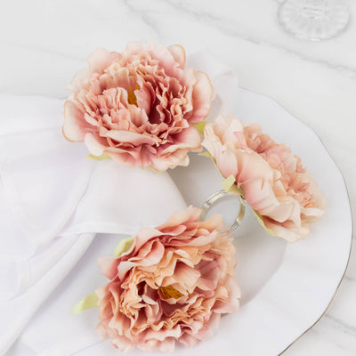 Floral napkin rings in soft pink hues on a white table setting.
