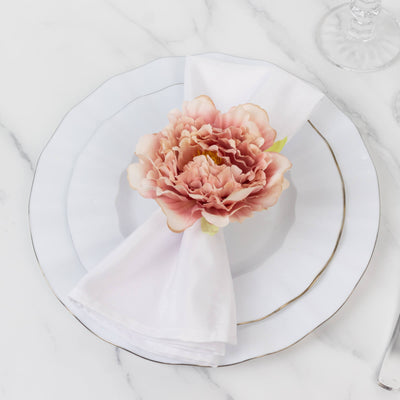 Elegant table setting with a pink flower on a white napkin and plate.