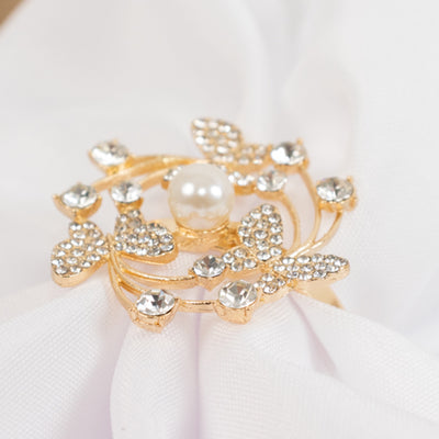 Gold butterfly brooch with pearl and rhinestones on white fabric.
