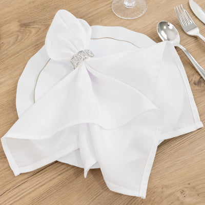 Elegant white napkin elegantly arranged on a dining plate with silver accents.