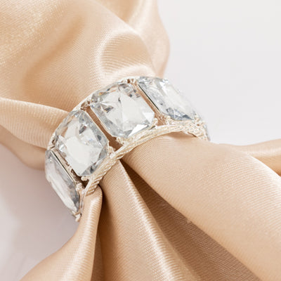 Elegant silver ring with large clear gemstones on a soft beige fabric.