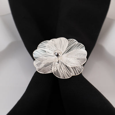Silver flower-shaped brooch on a black fabric background.