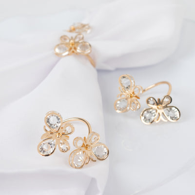 Gold butterfly earrings with crystal accents on a white fabric backdrop.