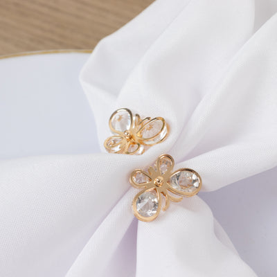 Gold butterfly napkin rings with crystal accents on a white napkin.