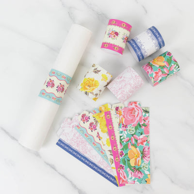 Colorful floral wrapping paper rolls and sheets arranged on a marble background.
