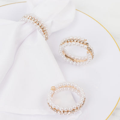 Elegant pearl and gold napkin rings on a decorative plate.