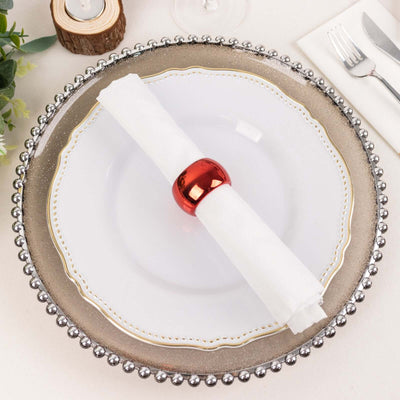 Elegant holiday table setting with a decorative plate and red napkin ring.