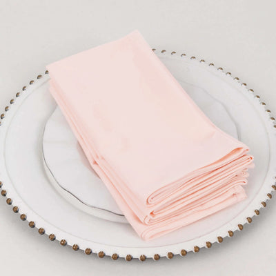 Folded pink napkins on a decorative plate.