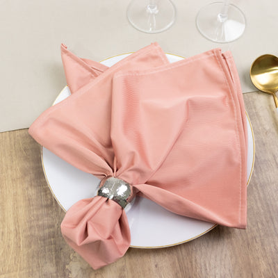 Elegant pink napkin with silver holder on a white plate.