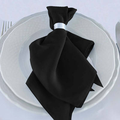 Elegant black napkin with silver ring on a white plate.
