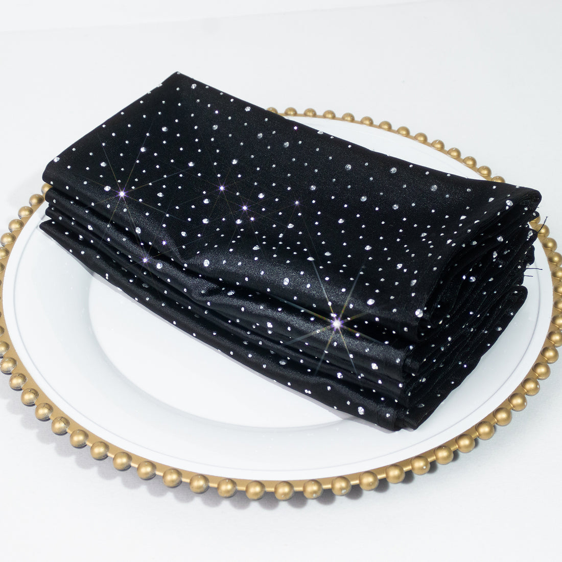 Black napkins with silver star pattern stacked on a decorative plate.