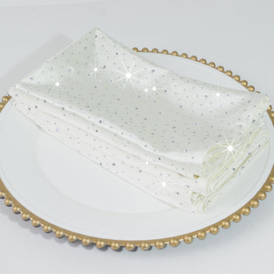White napkins with sparkling embellishments on a decorative plate.