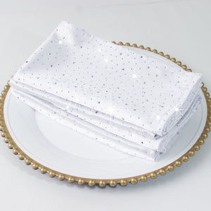 Elegant white napkins with sparkling details on a decorative plate.