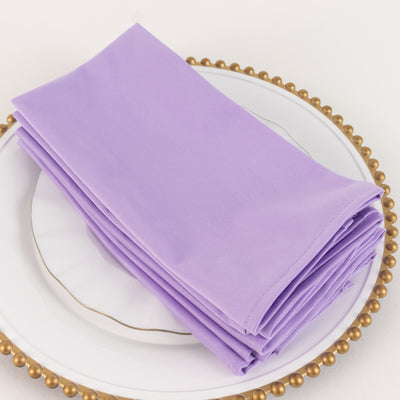 Purple fabric napkins neatly stacked on a decorative plate.