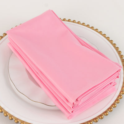 Stack of elegant pink napkins on a decorative plate.