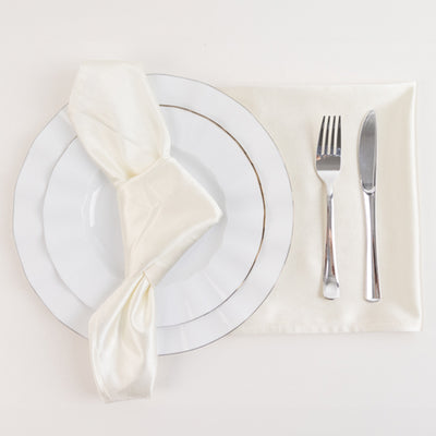 Elegant dinner setting with white plates, silverware, and a cream napkin.