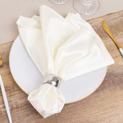 Elegant white napkin elegantly arranged with a silver napkin ring on a plate.
