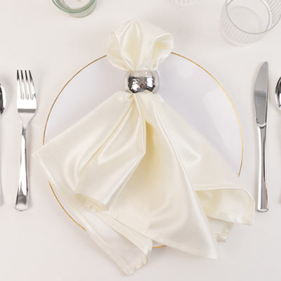 Elegant white satin napkin with silver ring on a gold-rimmed plate.
