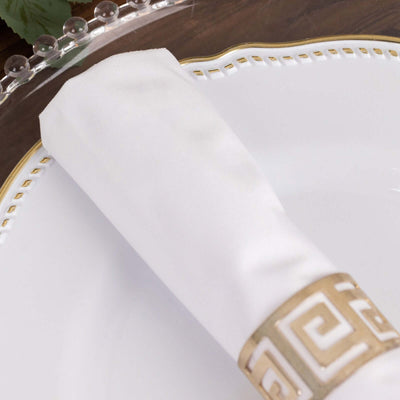 Elegant white napkin with gold-patterned ring on a decorative plate.