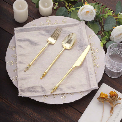 Gold cutlery set on a decorative plate with napkin and flowers.
