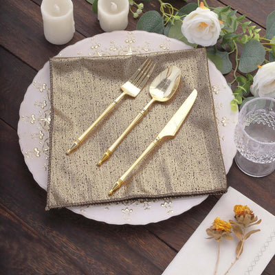 Elegant gold cutlery set on a decorative napkin with flowers and candles.