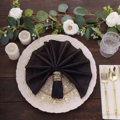 Elegant black napkin with gold ring on a decorative plate, surrounded by floral accents.