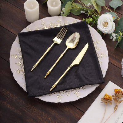 Elegant gold cutlery set on a black napkin atop a decorative plate.