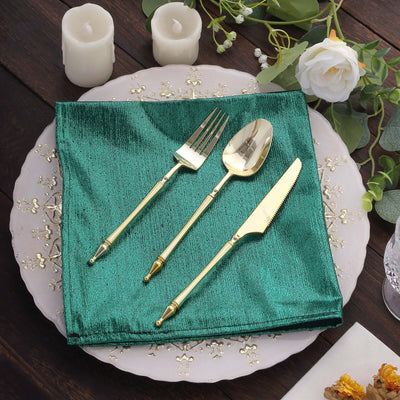 Elegant gold flatware set on a green napkin with decorative plate and candles.