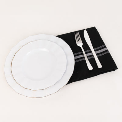 White dinner plate and side plate on a black napkin with silver utensils