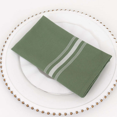 Green napkin with white stripes on a decorative plate.