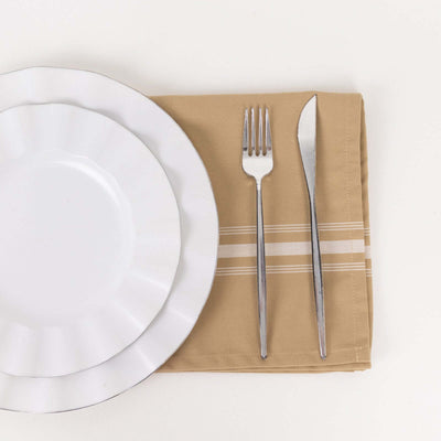 White dinner plates with silver cutlery on a beige napkin