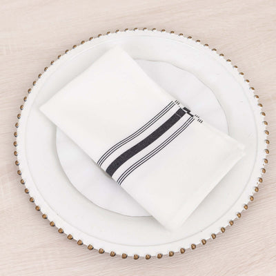 White napkin with black stripes on a decorative plate.